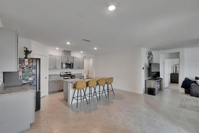 3628 Diving Dove Ln, Bartow, FL 33830 - kitchen featuring stainless steel appliances, a sink, a kitchen bar, gray cabinetry, and a kitchen island with sink