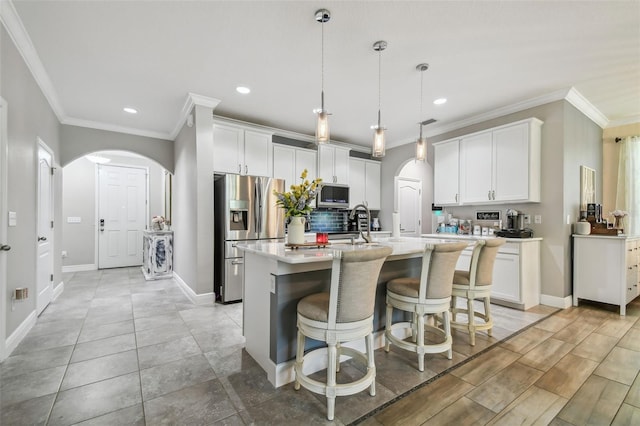 10512 Scenic Hollow Dr, Riverview, FL 33578 - kitchen featuring appliances with stainless steel finishes, arched walkways, ornamental molding, recessed lighting, and light countertops