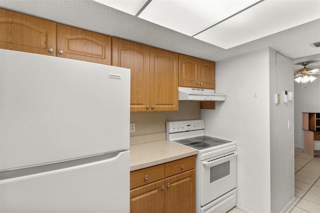 4500 E Bay Dr Unit 106, Clearwater, FL 33764 - kitchen with white appliances, under cabinet range hood, light tile patterned floors, light countertops, and brown cabinets