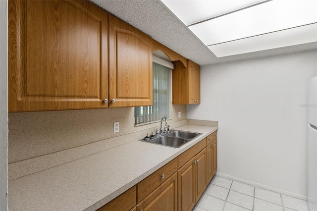 4500 E Bay Dr Unit 106, Clearwater, FL 33764 - kitchen featuring a sink, brown cabinets, light countertops, baseboards, and light tile patterned flooring