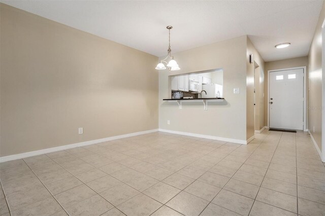 340 Causeway Blvd Unit 105, Dunedin, FL 34698 - empty room with light tile patterned flooring, baseboards, and a chandelier