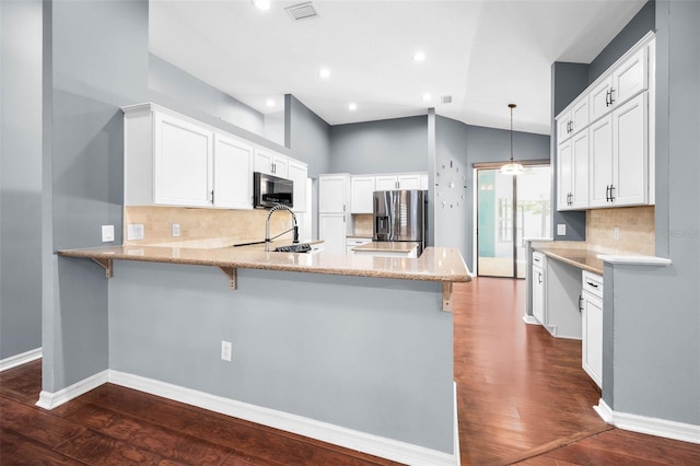2459 Parkstream Ave, Clearwater, FL 33759 - kitchen with appliances with stainless steel finishes, a peninsula, decorative backsplash, dark wood finished floors, and white cabinetry