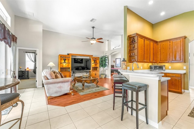 8814 N River Rd, Tampa, FL 33635 - kitchen featuring a towering ceiling, light tile patterned floors, arched walkways, brown cabinets, and light countertops