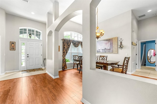 8814 N River Rd, Tampa, FL 33635 - foyer entrance with a high ceiling, arched walkways, baseboards, a chandelier, and light wood-style floors