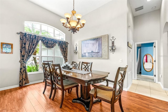 8814 N River Rd, Tampa, FL 33635 - dining room with a chandelier, a high ceiling, light wood-type flooring, and baseboards