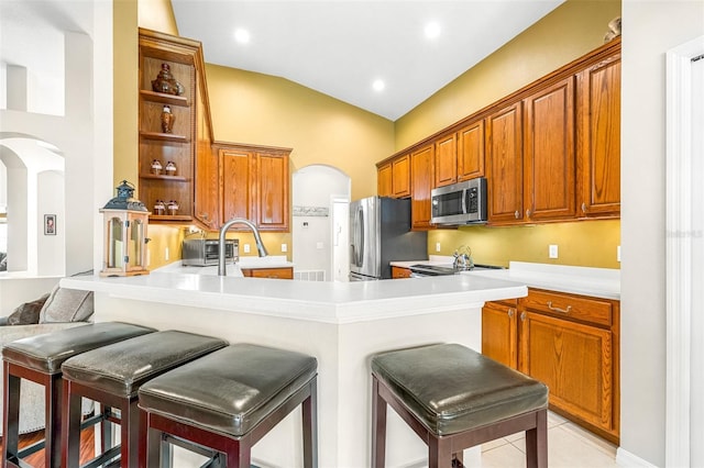 8814 N River Rd, Tampa, FL 33635 - kitchen featuring stainless steel appliances, open shelves, arched walkways, a peninsula, and a breakfast bar area