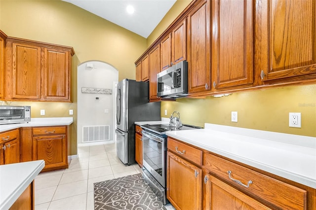 8814 N River Rd, Tampa, FL 33635 - kitchen featuring appliances with stainless steel finishes, arched walkways, brown cabinetry, and light countertops