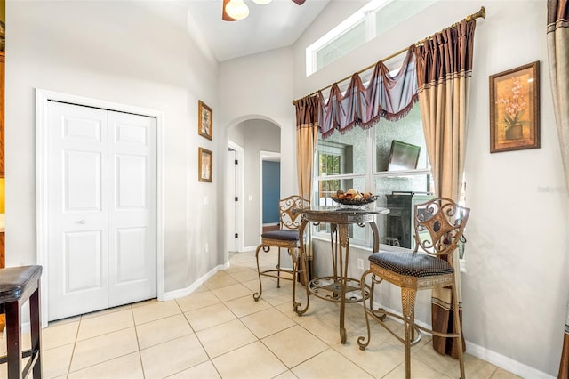 8814 N River Rd, Tampa, FL 33635 - tiled dining space with arched walkways, baseboards, a ceiling fan, and a towering ceiling