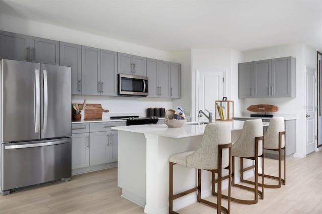 12782 Canter Call Rd, Lithia, FL 33547 - kitchen with stainless steel appliances, gray cabinetry, light wood-style flooring, and a sink