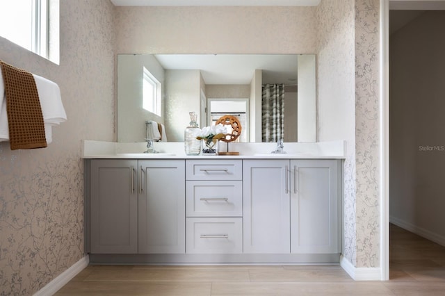 12782 Canter Call Rd, Lithia, FL 33547 - full bath featuring wallpapered walls, double vanity, wood finished floors, and baseboards