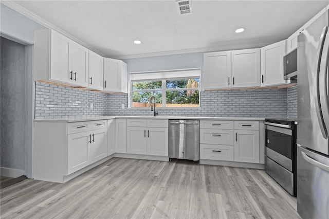 4841 Drift Tide Dr, New Port Richey, FL 34652 - kitchen featuring stainless steel appliances, light countertops, light wood-style flooring, white cabinetry, and crown molding