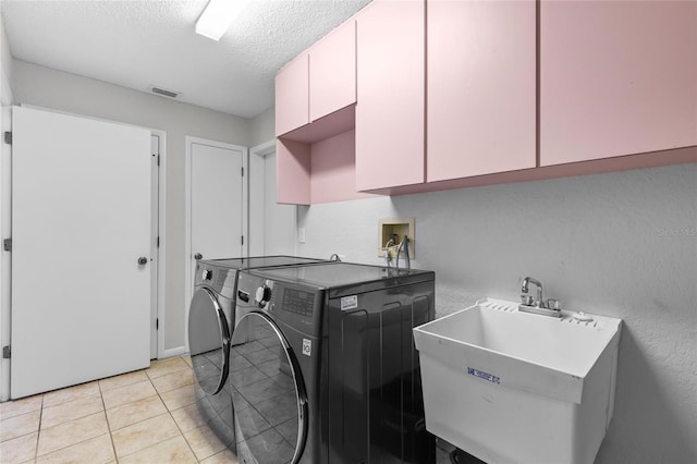 10446 Baylor Dr, Spring Hill, FL 34608 - washroom featuring cabinet space, washing machine and dryer, a textured ceiling, and light tile patterned flooring
