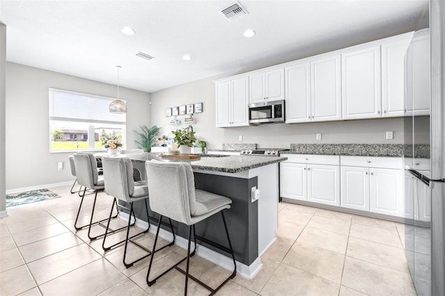 30762 Parrot Reef Ct, Wesley Chapel, FL 33545 - kitchen with stainless steel appliances, a kitchen bar, white cabinetry, recessed lighting, and light tile patterned floors