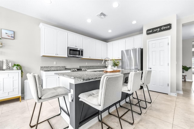 30762 Parrot Reef Ct, Wesley Chapel, FL 33545 - kitchen featuring stainless steel appliances, white cabinetry, a breakfast bar, recessed lighting, and stone countertops