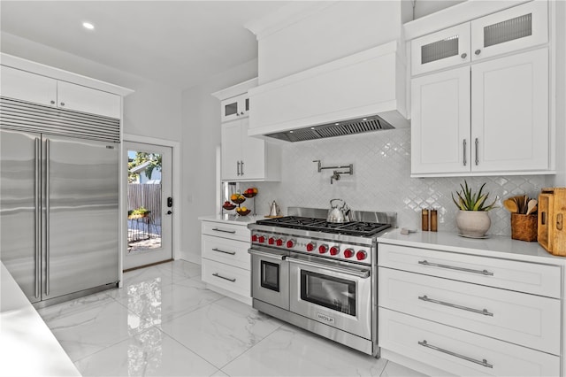 208 Live Oak Ln, Largo, FL 33770 - kitchen featuring high end appliances, premium range hood, white cabinets, light marble finish floors, and recessed lighting