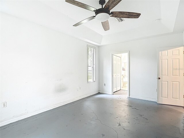 1332 Osceola Hollow Rd, Odessa, FL 33556 - unfurnished bedroom featuring concrete flooring, a tray ceiling, ensuite bath, baseboards, and ceiling fan