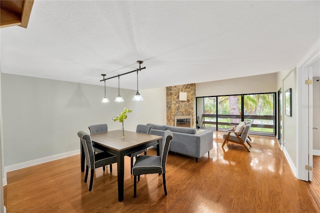 1111 N Bayshore Blvd Unit E10, Clearwater, FL 33759 - dining space featuring light wood finished floors, rail lighting, a stone fireplace, and a textured ceiling