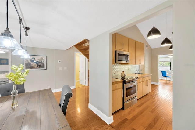 1111 N Bayshore Blvd Unit E10, Clearwater, FL 33759 - kitchen with appliances with stainless steel finishes, light brown cabinetry, light wood-style floors, tasteful backsplash, and vaulted ceiling