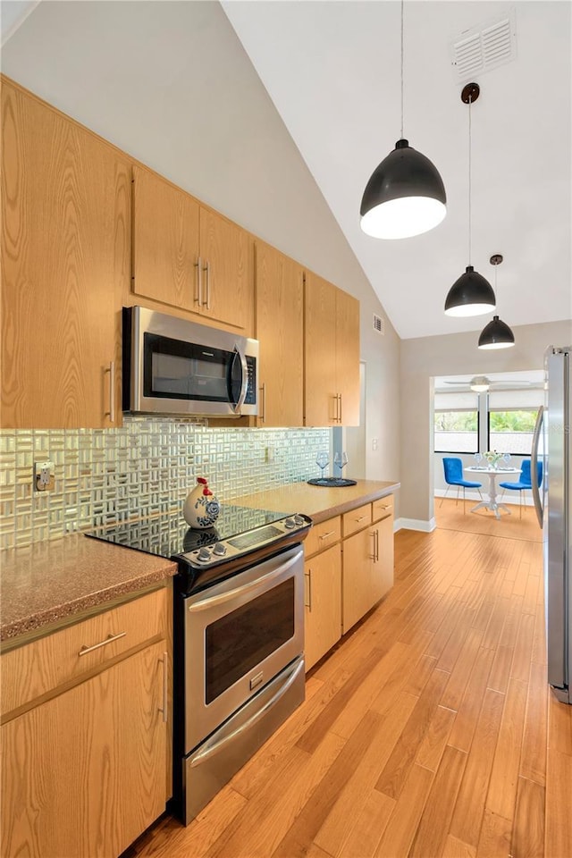 1111 N Bayshore Blvd Unit E10, Clearwater, FL 33759 - kitchen featuring stainless steel appliances, light brown cabinetry, tasteful backsplash, light wood finished floors, and decorative light fixtures
