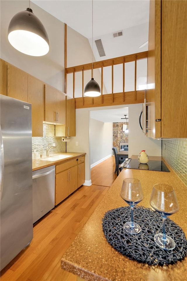 1111 N Bayshore Blvd Unit E10, Clearwater, FL 33759 - kitchen with appliances with stainless steel finishes, light wood-style flooring, a towering ceiling, backsplash, and light brown cabinets