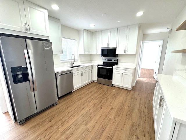 814 19th St SW, Largo, FL 33770 - kitchen with stainless steel appliances, a sink, white cabinetry, light wood-style floors, and light countertops
