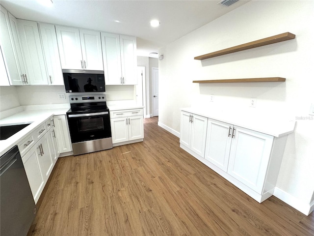 814 19th St SW, Largo, FL 33770 - kitchen with appliances with stainless steel finishes, light wood-style flooring, white cabinets, baseboards, and light countertops