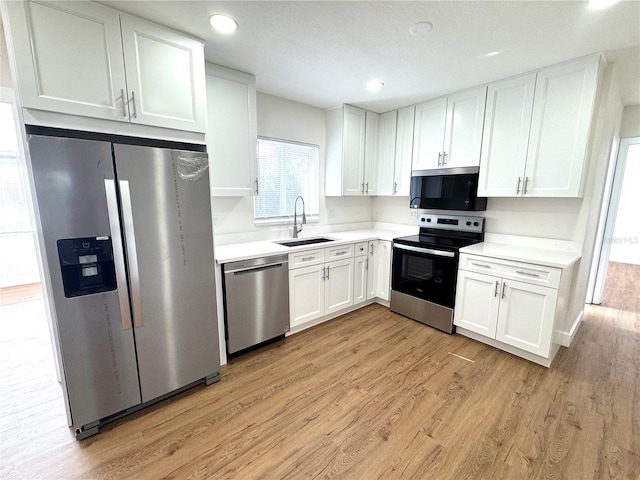 814 19th St SW, Largo, FL 33770 - kitchen featuring stainless steel appliances, a sink, light wood-style flooring, white cabinetry, and light countertops