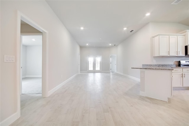 16433 66th Ln E, Parrish, FL 34219 - kitchen with white cabinets, light stone counters, light wood-style floors, open floor plan, and recessed lighting