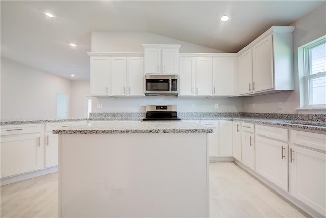 16433 66th Ln E, Parrish, FL 34219 - kitchen featuring stainless steel appliances, a kitchen island, white cabinets, light stone countertops, and vaulted ceiling