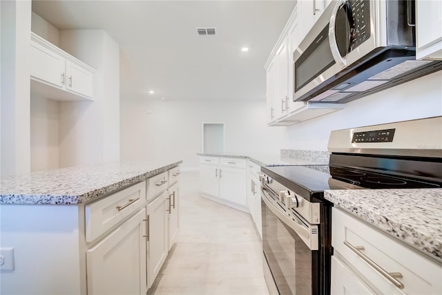 16433 66th Ln E, Parrish, FL 34219 - kitchen featuring appliances with stainless steel finishes, white cabinetry, light stone counters, recessed lighting, and a center island