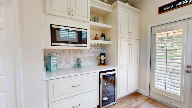 9800 Sago Point Dr, Seminole, FL 33777 - indoor dry bar with wine cooler, stainless steel microwave, decorative backsplash, and light wood-style flooring