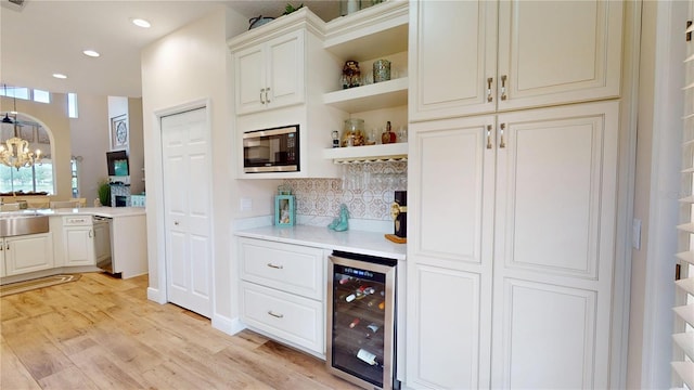9800 Sago Point Dr, Seminole, FL 33777 - indoor dry bar featuring wine cooler, stainless steel microwave, backsplash, a chandelier, and light wood finished floors