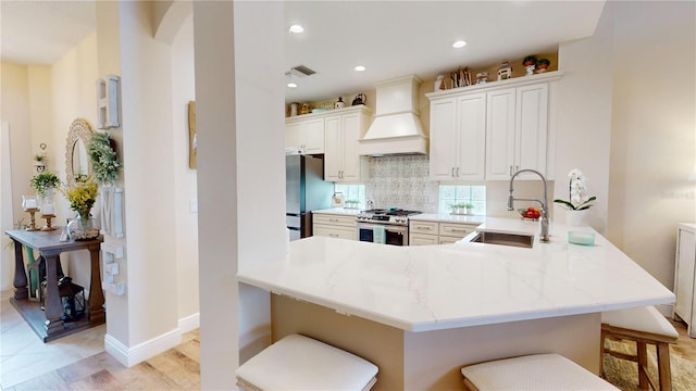 9800 Sago Point Dr, Seminole, FL 33777 - kitchen with stainless steel appliances, premium range hood, a breakfast bar, a sink, and backsplash