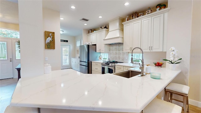 9800 Sago Point Dr, Seminole, FL 33777 - kitchen with appliances with stainless steel finishes, a sink, custom range hood, decorative backsplash, and a peninsula