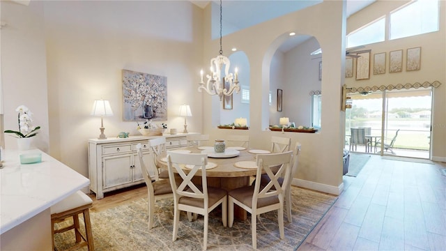 9800 Sago Point Dr, Seminole, FL 33777 - dining area featuring a high ceiling, plenty of natural light, a chandelier, light wood-style floors, and arched walkways