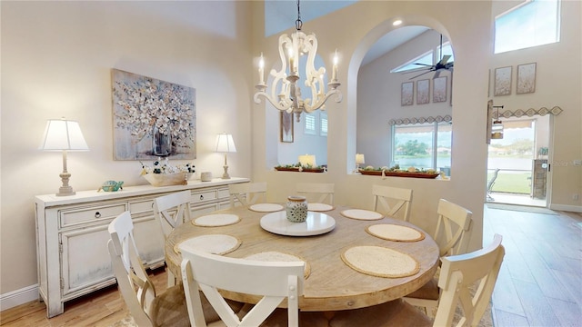 9800 Sago Point Dr, Seminole, FL 33777 - dining room featuring a towering ceiling, light wood-style flooring, arched walkways, healthy amount of natural light, and a chandelier