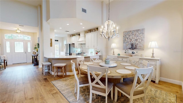 9800 Sago Point Dr, Seminole, FL 33777 - dining area with a towering ceiling, light wood-style flooring, a chandelier, and baseboards