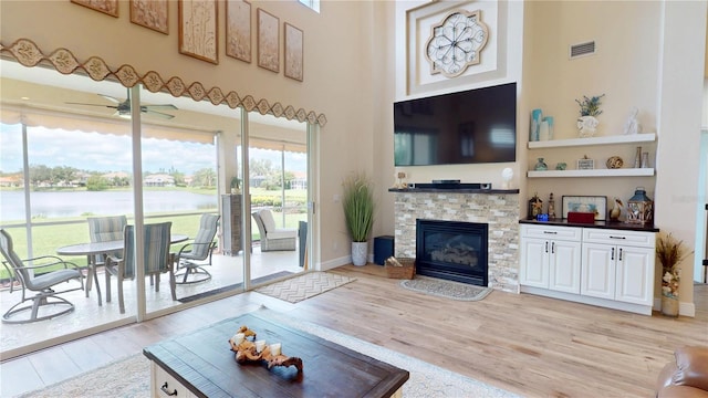 9800 Sago Point Dr, Seminole, FL 33777 - living area with light wood-style floors, a towering ceiling, a ceiling fan, a stone fireplace, and baseboards