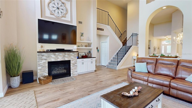 9800 Sago Point Dr, Seminole, FL 33777 - living room featuring a towering ceiling, stairs, light wood-style flooring, baseboards, and arched walkways