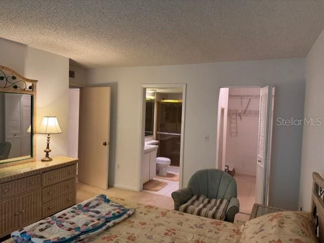 1258 Pine Ridge Cir W Unit F1, Tarpon Springs, FL 34688 - bedroom with a textured ceiling, a closet, connected bathroom, light carpet, and a spacious closet
