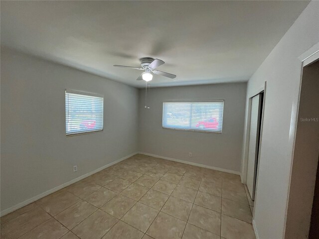 422 Crosswinds Dr, Palm Harbor, FL 34683 - unfurnished bedroom featuring multiple windows, light tile patterned floors, a ceiling fan, and baseboards