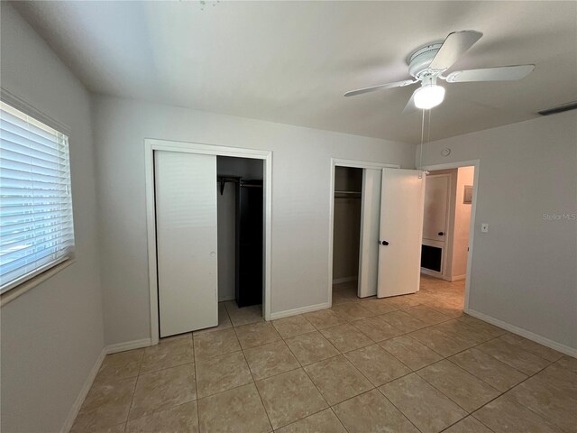 422 Crosswinds Dr, Palm Harbor, FL 34683 - unfurnished bedroom with two closets, light tile patterned floors, baseboards, and ceiling fan