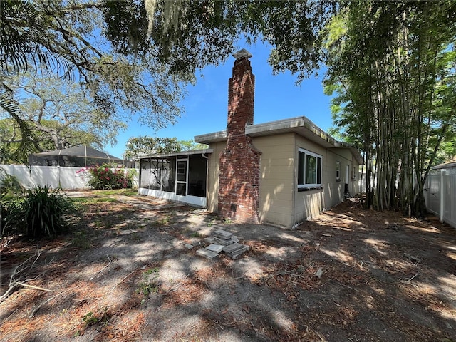 422 Crosswinds Dr, Palm Harbor, FL 34683 - rear view of property with a sunroom, a chimney, and concrete block siding