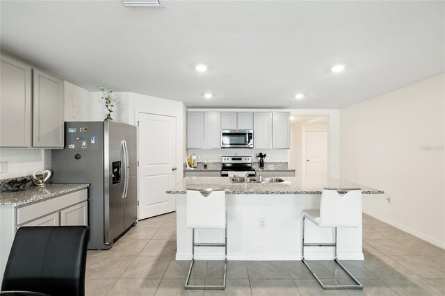 10452 Elgin Blvd, Spring Hill, FL 34608 - kitchen featuring appliances with stainless steel finishes, light tile patterned floors, an island with sink, recessed lighting, and a kitchen bar