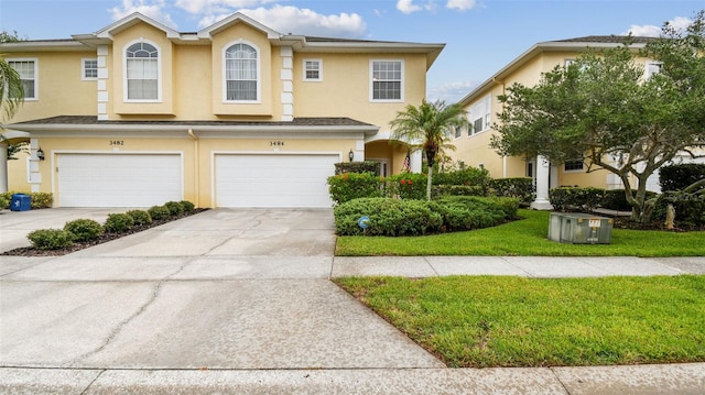 3484 Primrose Way, Palm Harbor, FL 34683 - townhome / multi-family property featuring stucco siding, a front yard, driveway, and a garage