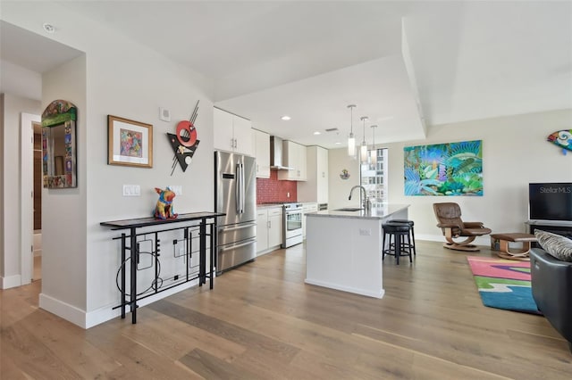 199 Dali Blvd Unit 607, Saint Petersburg, FL 33701 - kitchen with stainless steel appliances, a sink, wall chimney exhaust hood, a breakfast bar, and white cabinets