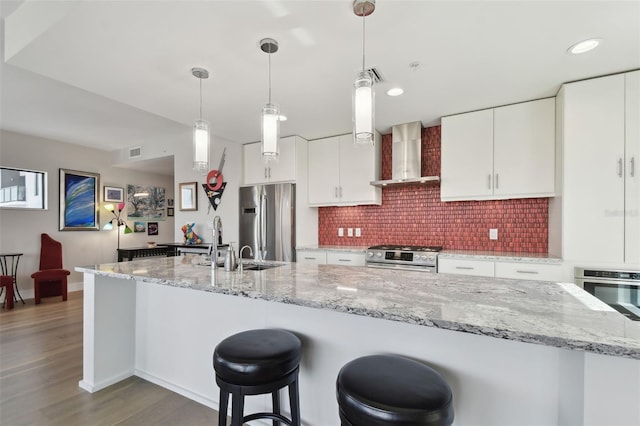 199 Dali Blvd Unit 607, Saint Petersburg, FL 33701 - kitchen with appliances with stainless steel finishes, wall chimney range hood, decorative backsplash, wood finished floors, and a breakfast bar