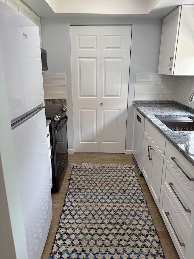 1055 6th Ave Unit A11, Vero Beach, FL 32960 - kitchen featuring white appliances, light stone counters, white cabinets, a sink, and decorative backsplash