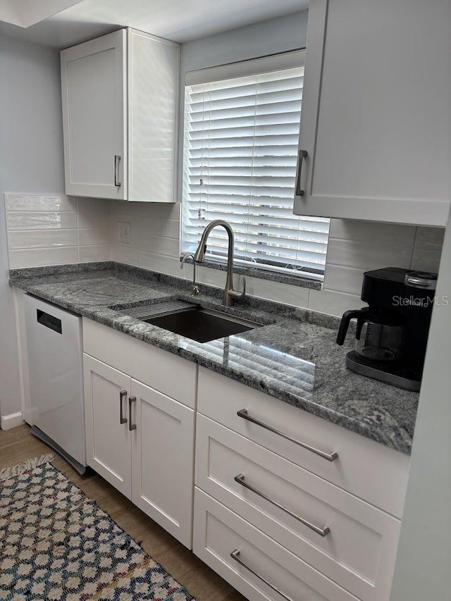 1055 6th Ave Unit A11, Vero Beach, FL 32960 - kitchen featuring dishwashing machine, a sink, white cabinets, and dark stone counters
