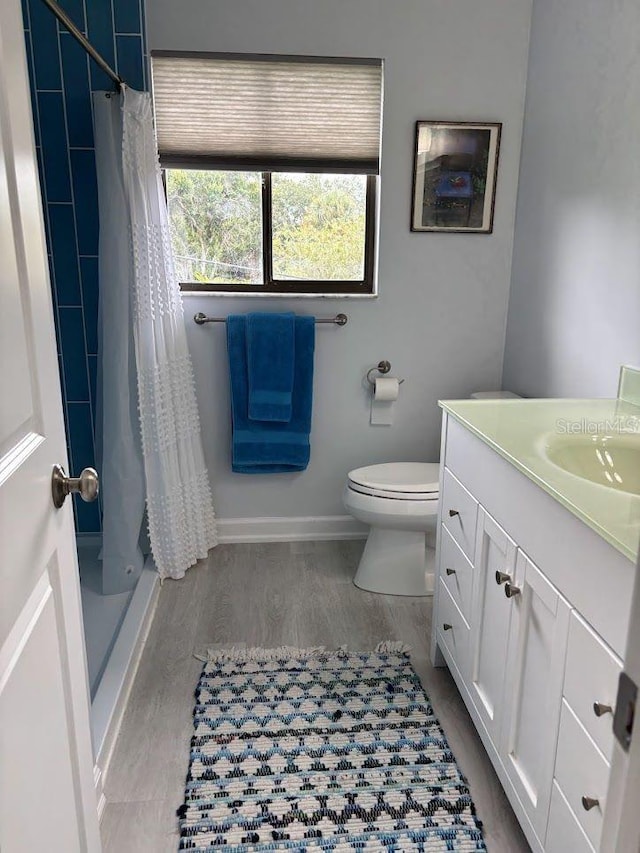 1055 6th Ave Unit A11, Vero Beach, FL 32960 - full bath featuring vanity, toilet, a shower stall, wood finished floors, and baseboards